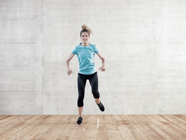 une femme en tenue de sport saute d’une jambe sur l’autre.