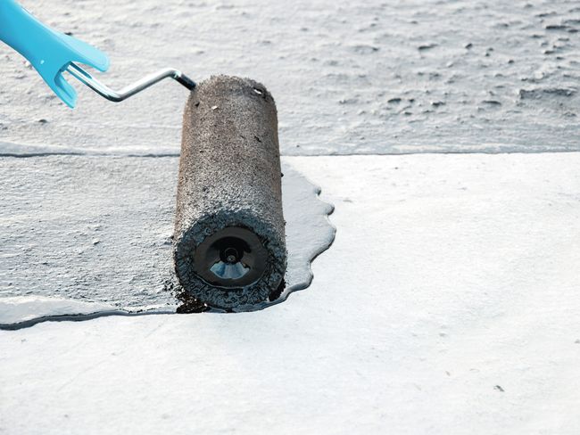 Dieses Foto zeigt eine Walze, mit der ein rutschhemmender Anstrich auf einen Boden aufgetragen wird. Das sorgt für Sicherheit auf Verkehrswegen.