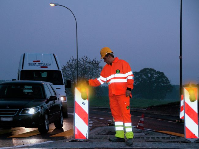 Lavori stradali, il personale indossa indumenti di protezione di colore arancione in condizioni di semioscurità