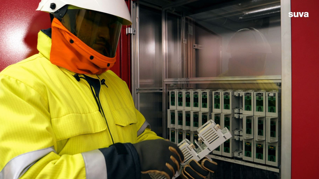 Un elettricista installatore indossa dispositivi di protezione mentre lavora all’armadio elettrico