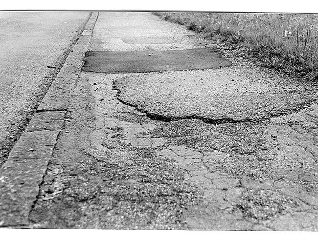 La foto mostra un asfalto che presenta dei difetti visibili. Ad esempio, il dislivello è troppo elevato.
