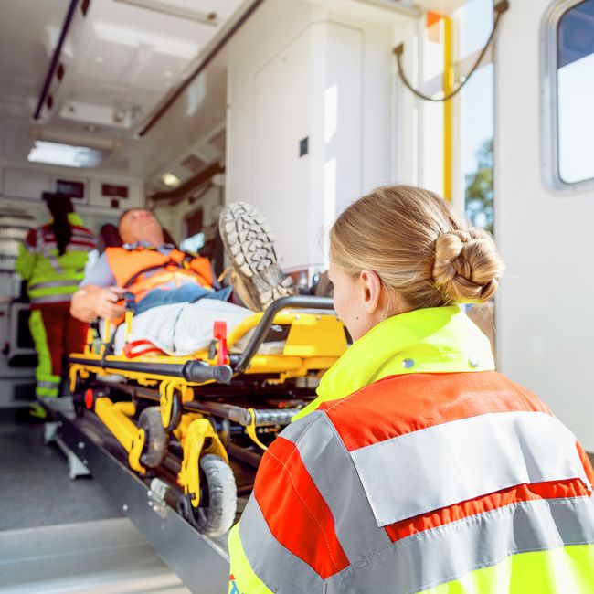 Rettungsdienst schiebt Mann auf einer Trage in einen Krankenwagen