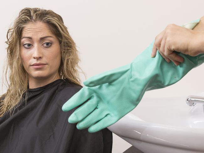 Image symbole: Une cliente regarde les gants de sa coiffeuse l’air dubitatif.