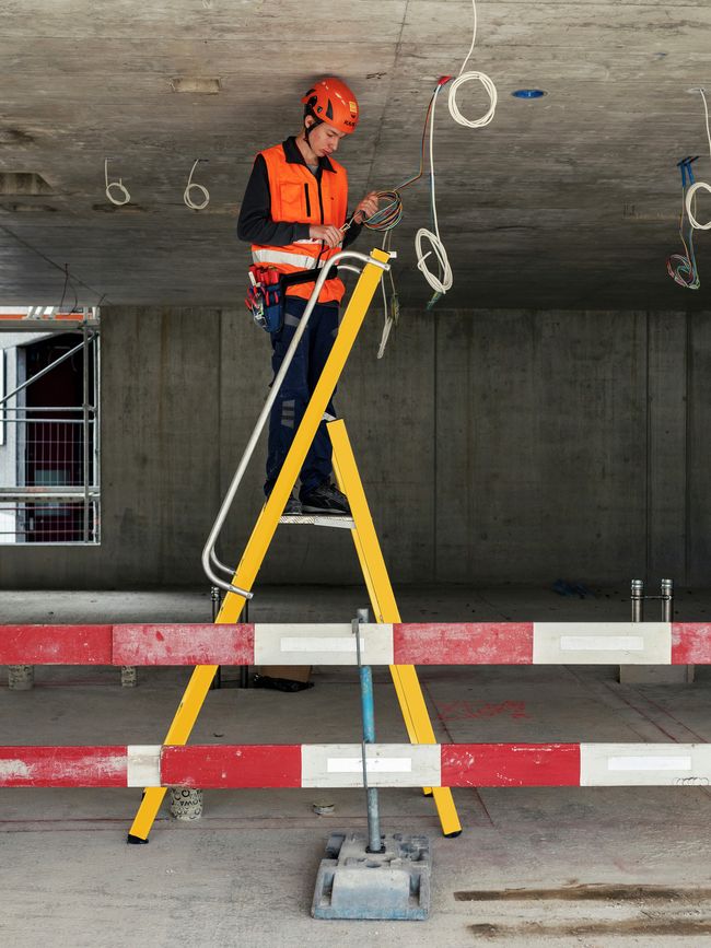 Un électricien au cours d’une installation avec une échelle à plateforme légère