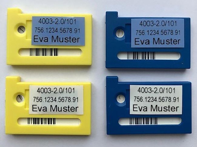 Es sind zwei gelbe Dosimeter sowie zwei blaue Dosimeter abgebildet. Pro Farbe hat es je einmal eine weisse und eine blau Etikette.