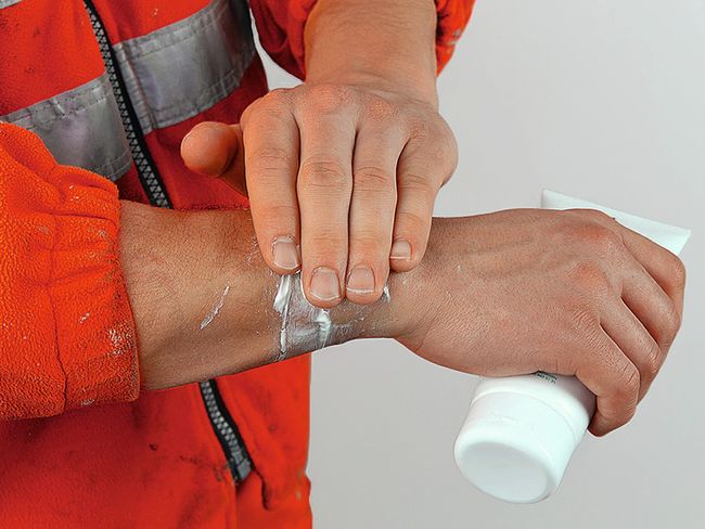 Un lavoratore si spalma la crema protettiva per le mani sul polso.