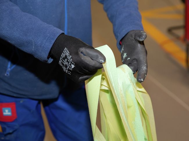 Un collaboratore con i guanti raccoglie pezzi di nastro adesivo contaminato.
