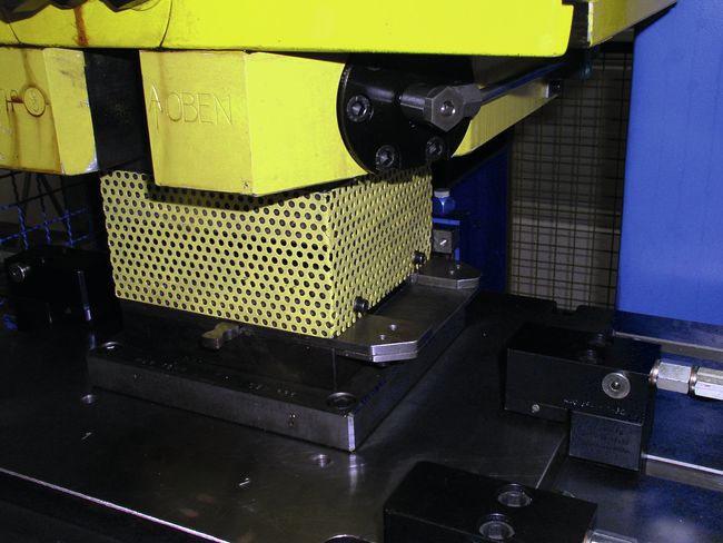 Ein Werkzeug, das für die Bearbeitung von Bandmaterial zum Einsatz kommt, ist mit einem gelben Gitter gesichert.