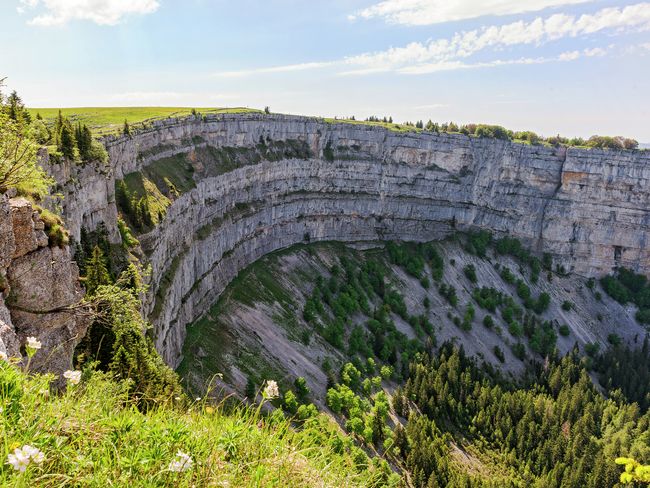 Der Creux-du-Van im Kanton Neuenburg in der Schweiz ist ein schöner Naturort mit runden Klippen. Die beeindruckenden Felsen umgeben eine flache Senke.