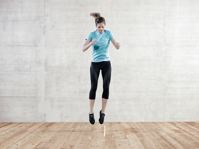 une femme en tenue de sport saute latéralement, le long d’une ligne imaginaire.