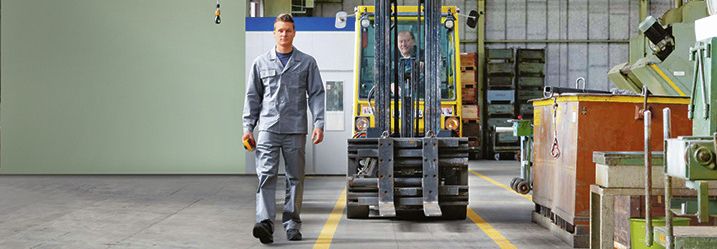 Klar markierter Verkehrsweg für einen Stapler, ein Mitarbeiter läuft ausserhalb des Fahrwegs.