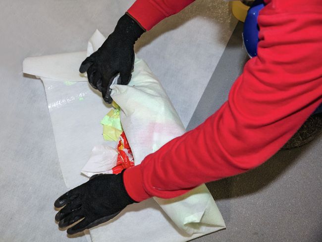 Un ouvrier en train d’enrouler des déchets dans une feuille de plastique.