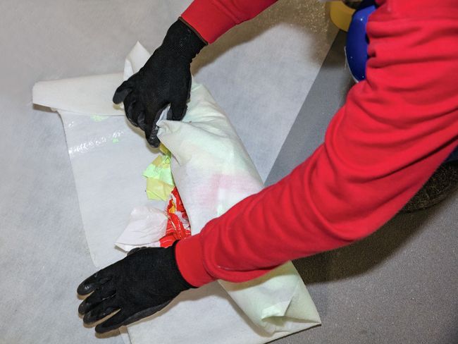 Ein Arbeiter rollt Abfälle in eine Plastikfolie ein.