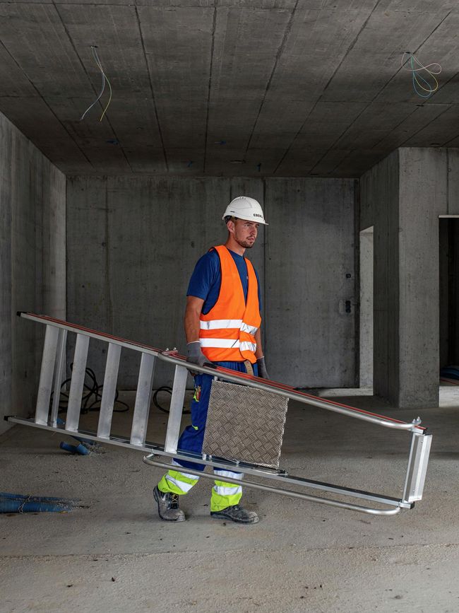 Un operaio porta una scala leggera con piattaforma.