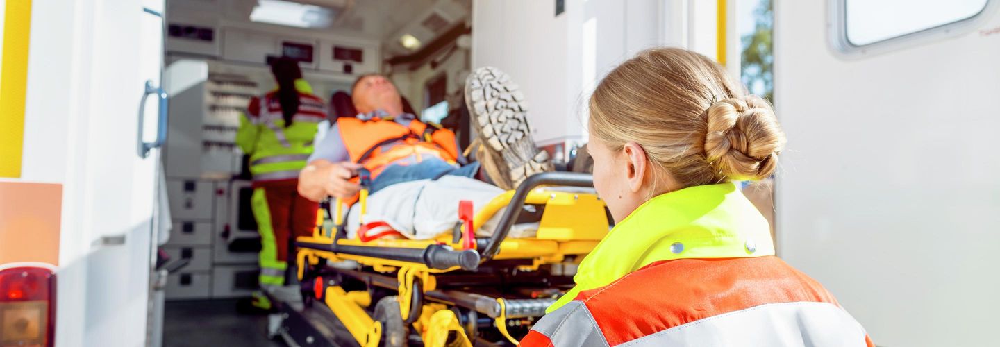 Rettungsdienst schiebt Mann auf einer Trage in einen Krankenwagen