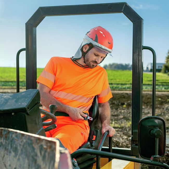 Un ouvrier est assis dans une machine de construction et veut mettre sa ceinture de sécurité.