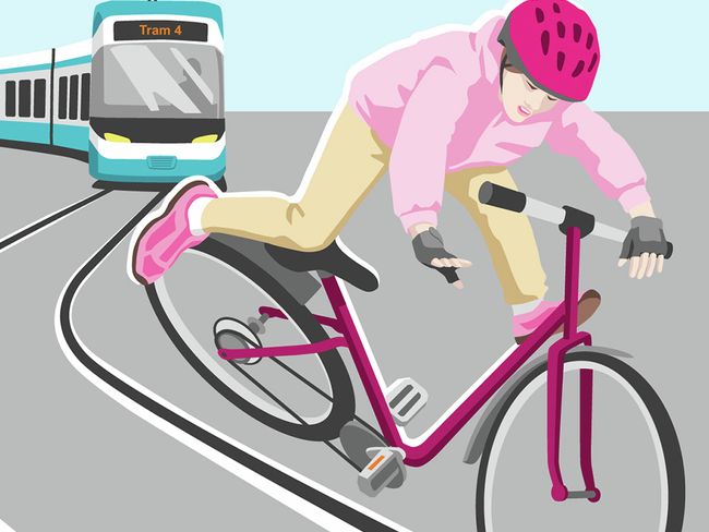 Eine Velofahrerin bleibt mit dem Velo in den Tramschienen hängen und droht zu fallen. Hinter ihr nähert sich ein Tram.