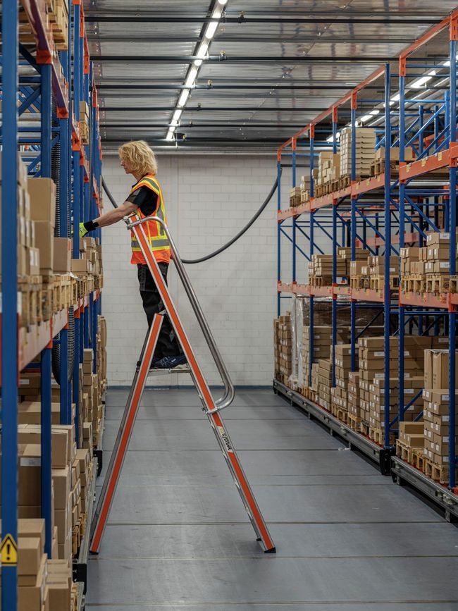 Échelle à plateforme légère dans le magasin à hauts rayonnages