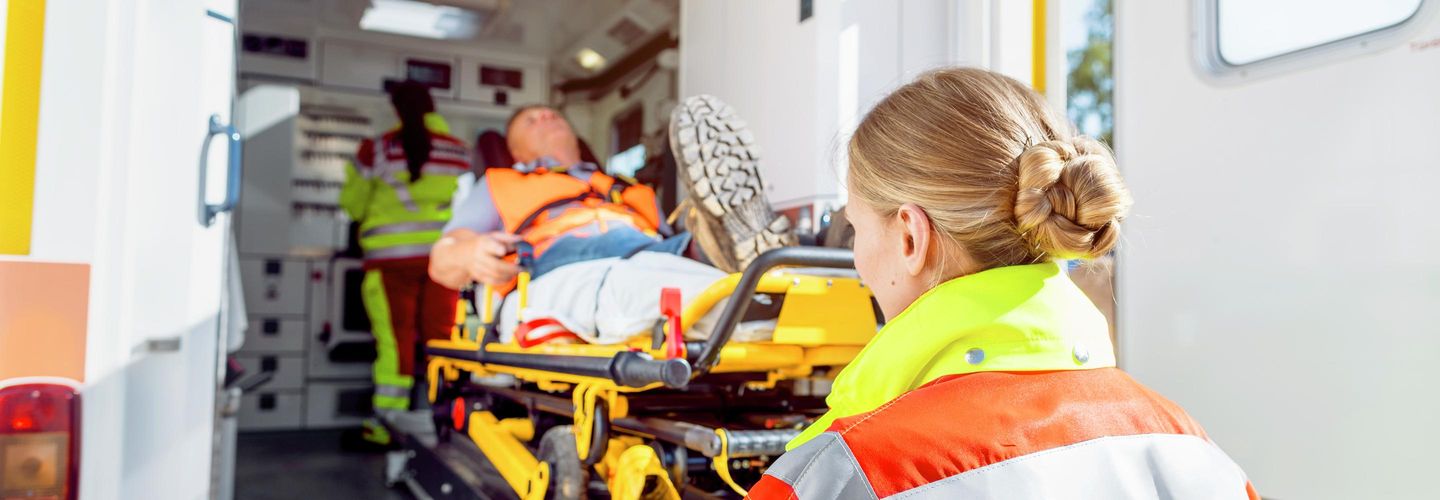 Rettungsdienst schiebt Mann auf einer Trage in einen Krankenwagen