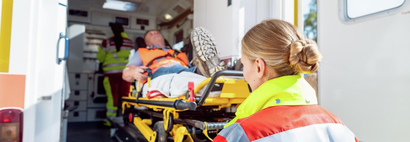Rettungsdienst schiebt Mann auf einer Trage in einen Krankenwagen