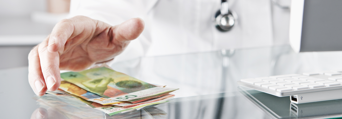 Arzt am Schreibtisch greift nach Bargeld