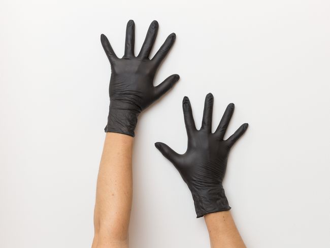 Hände mit schwarzen Nitril-Handschuhen.