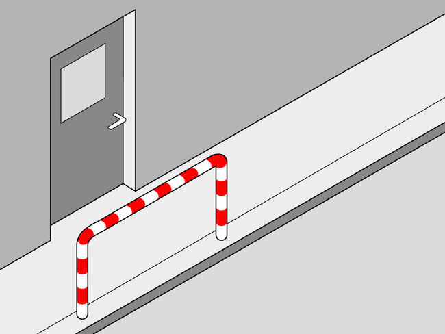Una barriera a strisce bianche e rosse è posta davanti alle porte di un capannone e previene l’invasione della corsia di marcia dei veicoli.