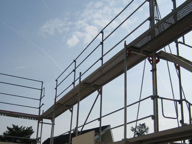 Échafaudage de façade avec garde-corps extérieur, photographié de l’intérieur d’un ouvrage en construction