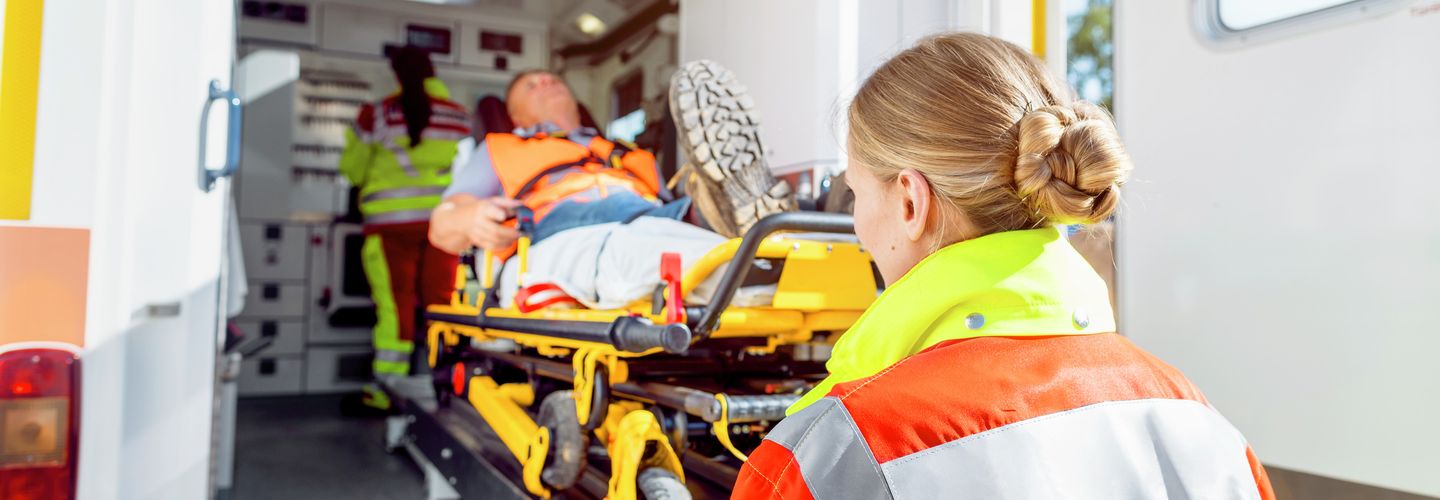 Rettungsdienst schiebt Mann auf einer Trage in einen Krankenwagen