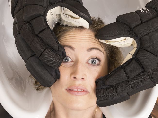 Image symbole: Un coiffeur essaie de laver des cheveux avec des gants de hockey.